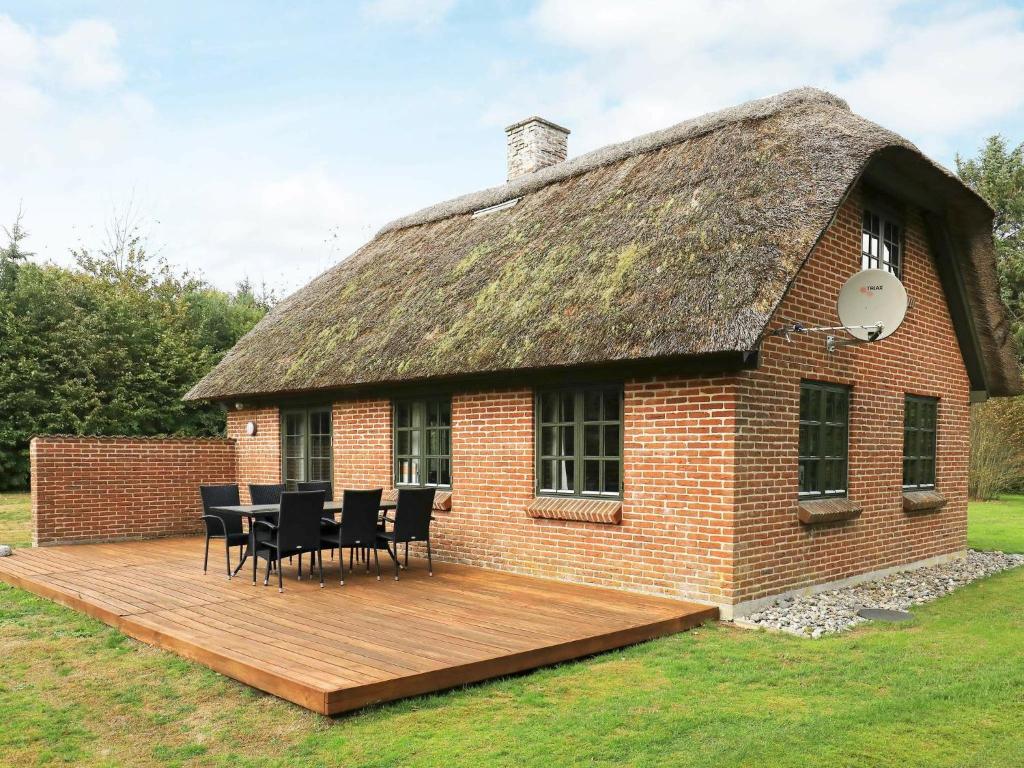 a house with a thatched roof with a wooden deck at 6 person holiday home in Ulfborg in Øhuse