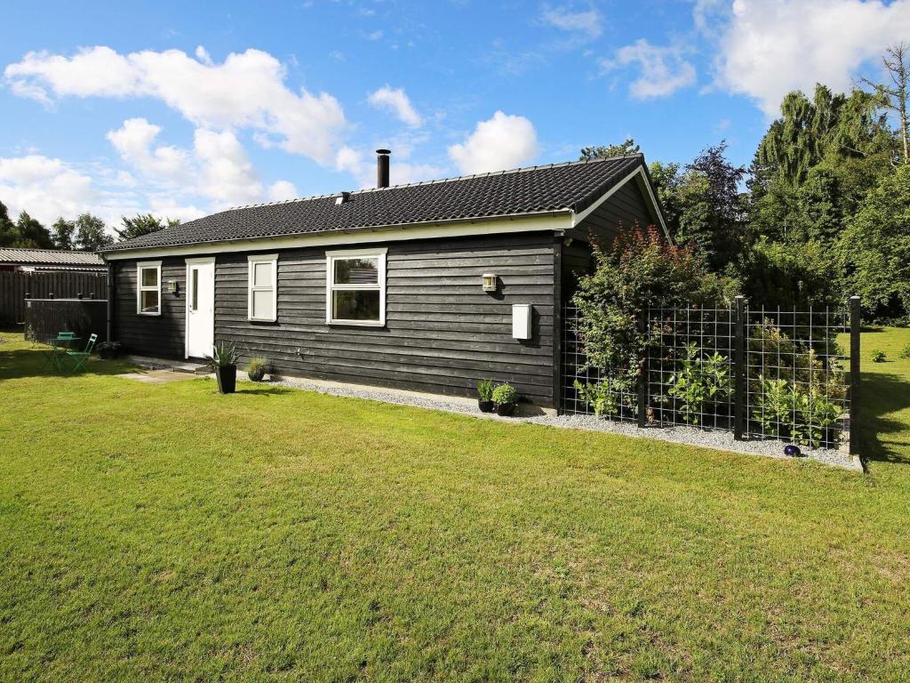 una pequeña casa con una valla en un patio en 5 person holiday home in J gerspris en Jægerspris
