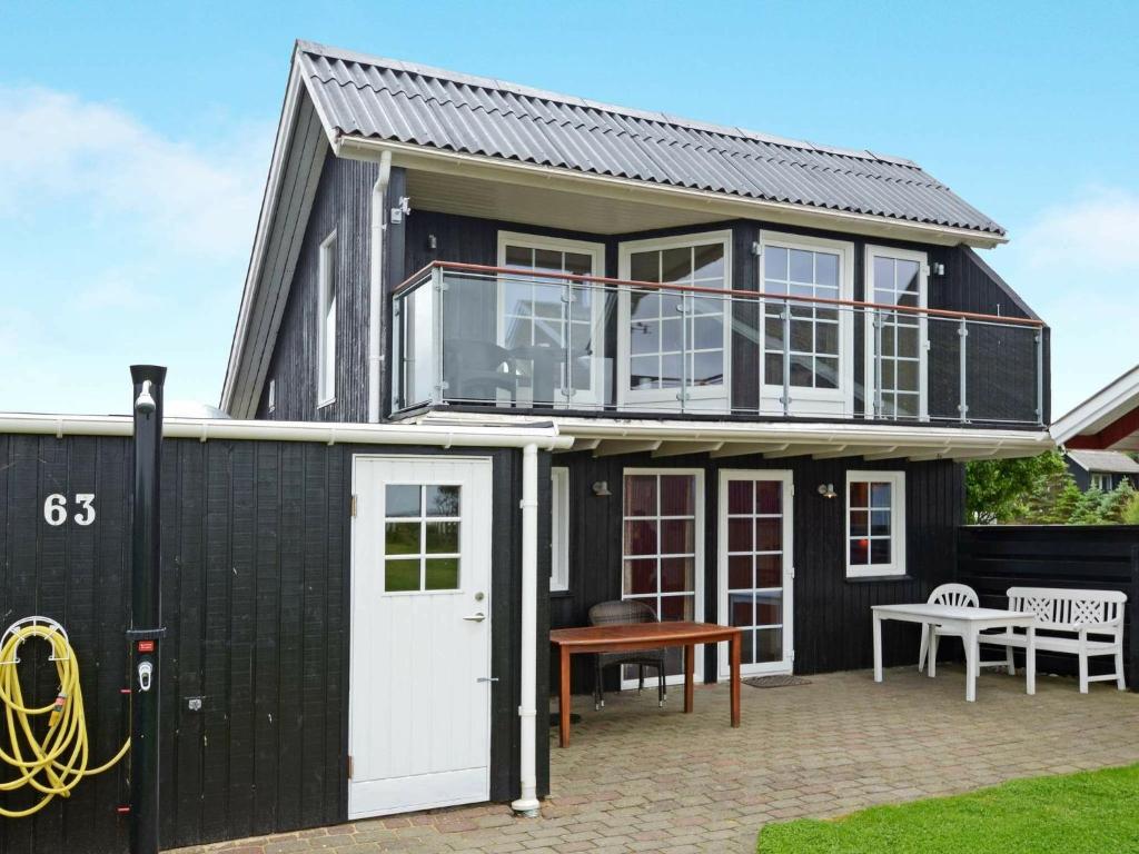 a black house with a white door and a patio at 6 person holiday home in Hemmet in Falen