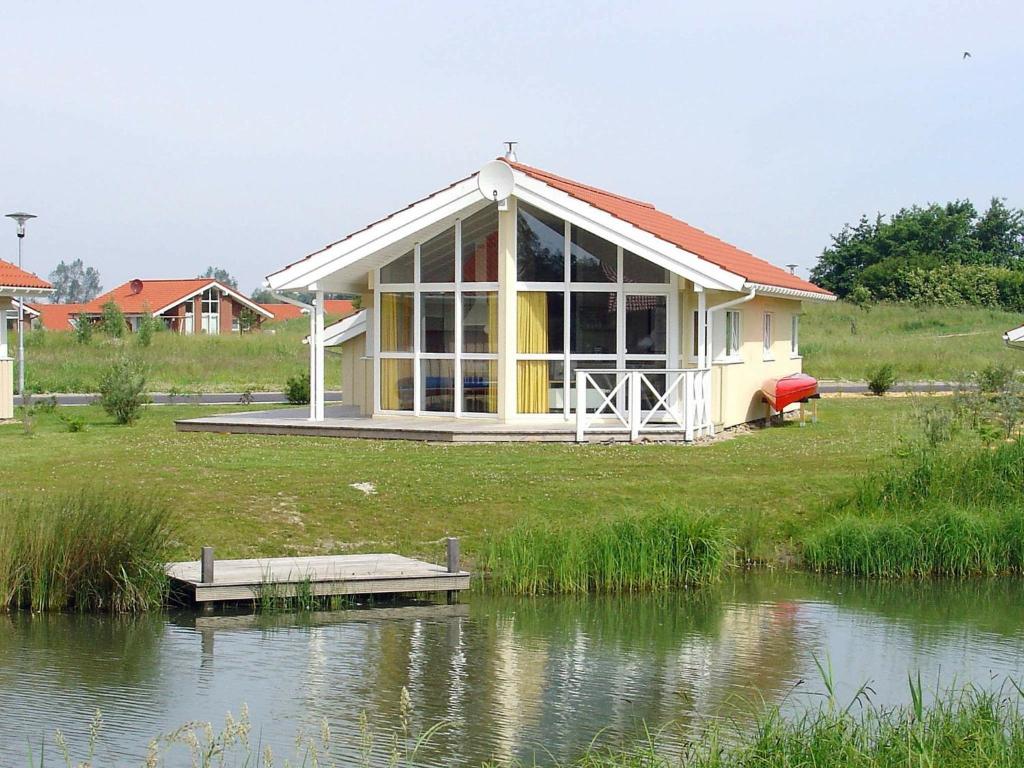 a house with a red roof next to a lake at 5 person holiday home in Otterndorf in Otterndorf