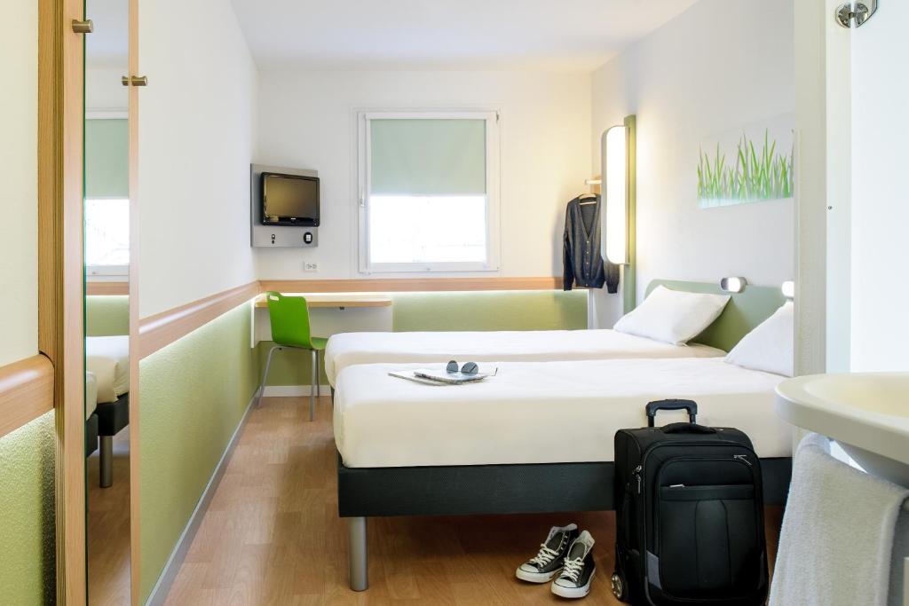 a hotel room with a bed and a suitcase at Ibis budget München Airport Erding in Erding