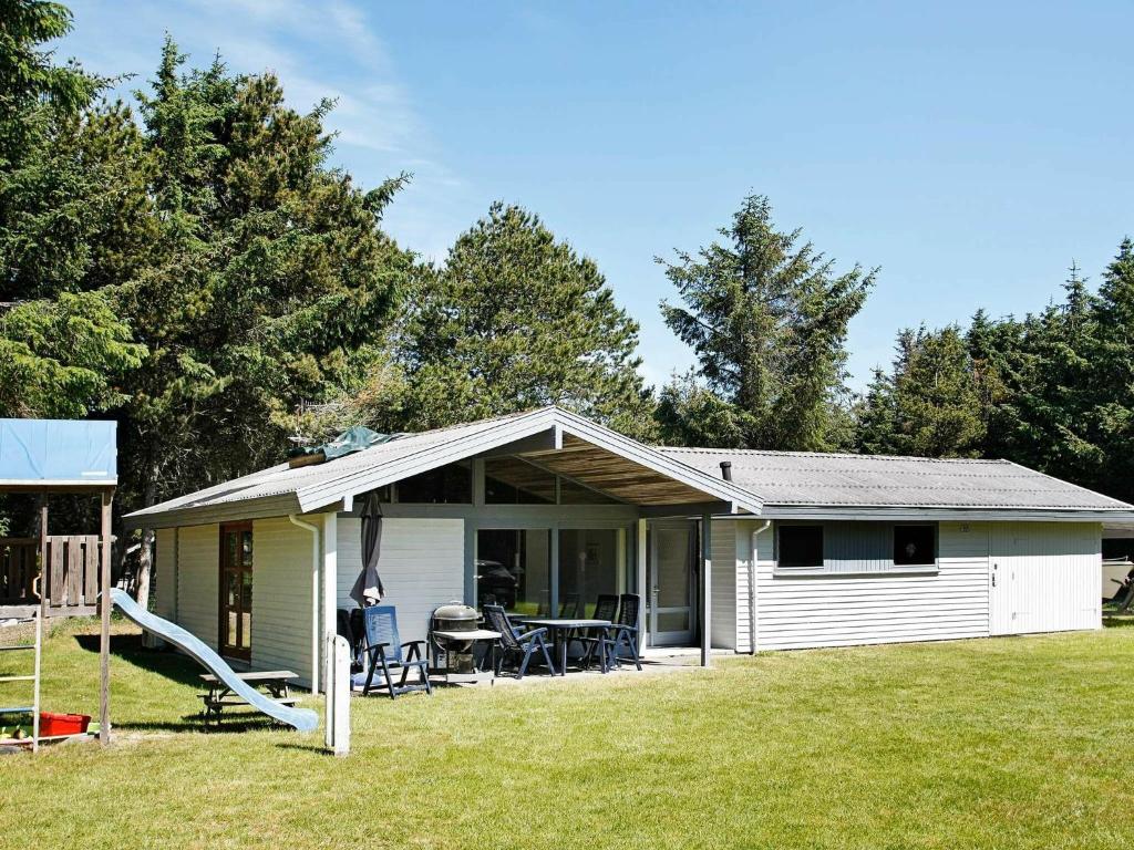 a small white house with a table and chairs at 6 person holiday home in L kken in Løkken