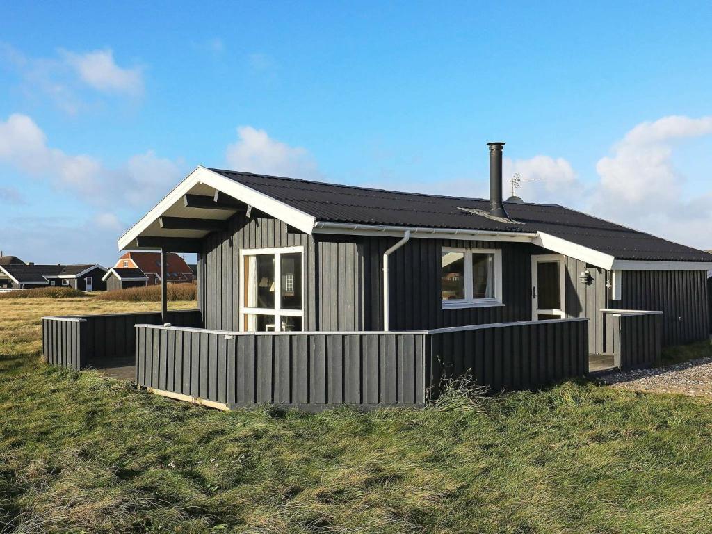 a black and white house sitting on top of a field at 8 person holiday home in Harbo re in Harboør