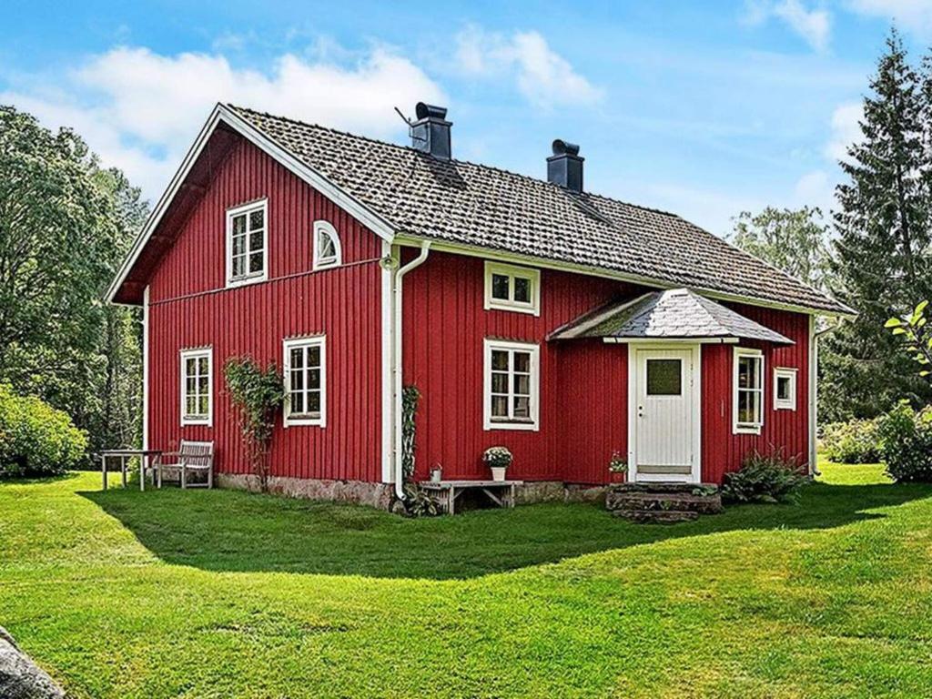 ein rotes Haus mit einer weißen Tür im Hof in der Unterkunft Holiday home SKILLINGARYD in Skillingaryd