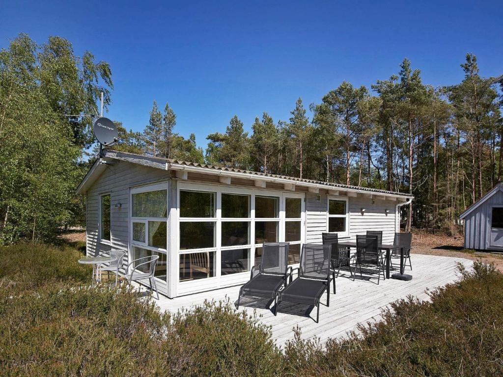 a white cabin with chairs on a deck at 4 person holiday home in Nex in Neksø
