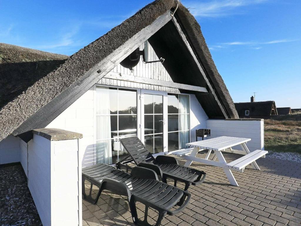 una casa con 2 sillas y una mesa de picnic en un patio en 8 person holiday home in Ringk bing, en Klegod
