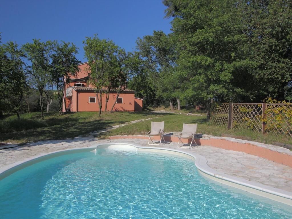 a swimming pool with two chairs and a house at Belvilla by OYO Casale le Querce in Cossignano