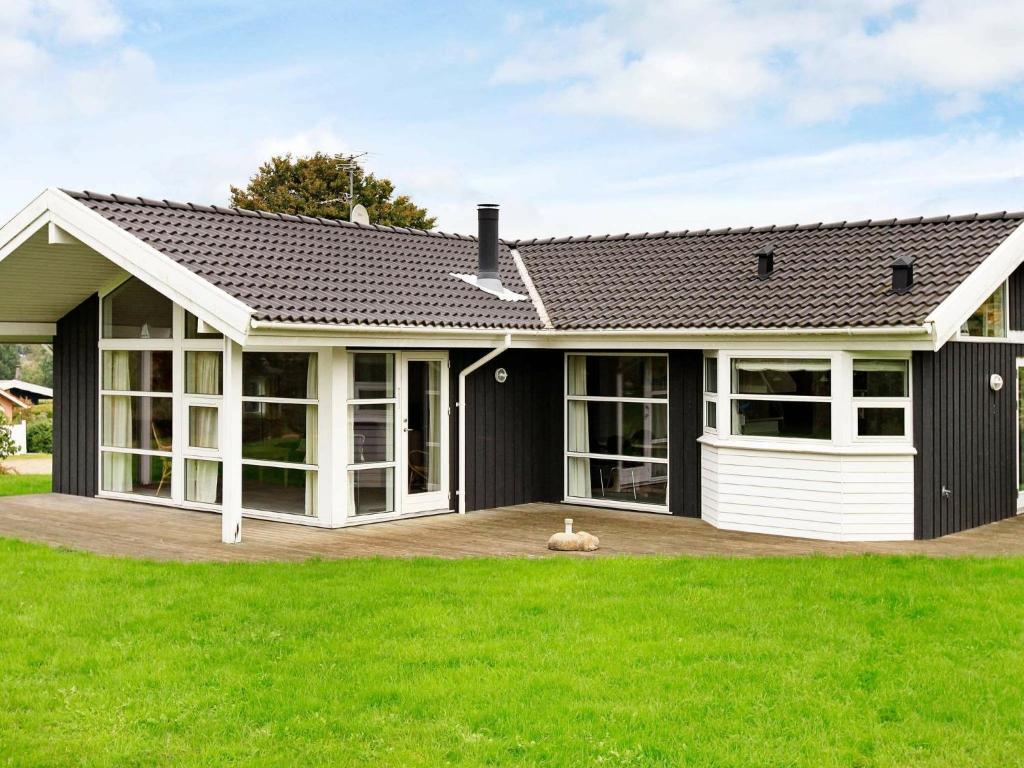 a house with a black roof and green grass at Three-Bedroom Holiday home in Hejls 7 in Hejls