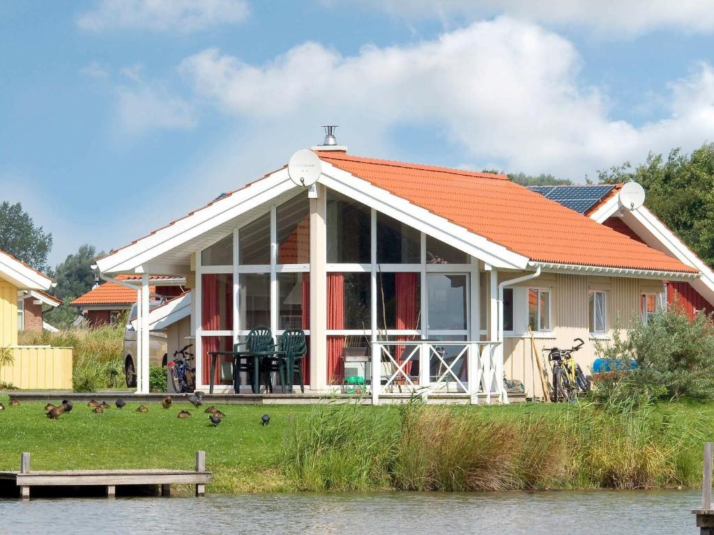 ein Haus mit einem orangenen Dach neben einem Wasserkörper in der Unterkunft 6 person holiday home in Otterndorf in Otterndorf