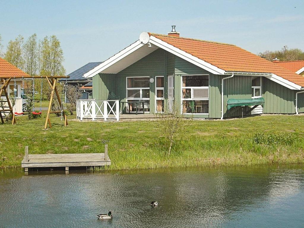 une maison verte avec deux canards nageant dans l'eau dans l'établissement 6 person holiday home in Otterndorf, à Otterndorf
