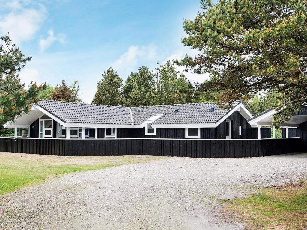 una casa en blanco y negro con una valla negra en 8 person holiday home in Bl vand, en Blåvand