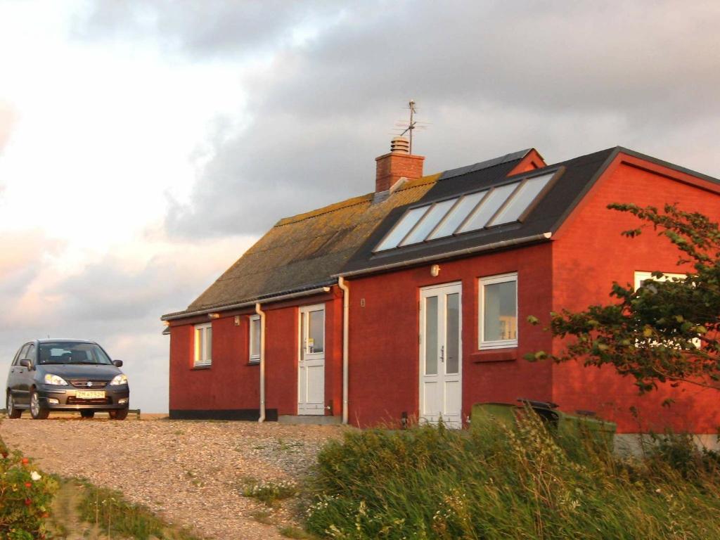 una casa roja con un coche aparcado al lado en 4 person holiday home in Lemvig, en Trans