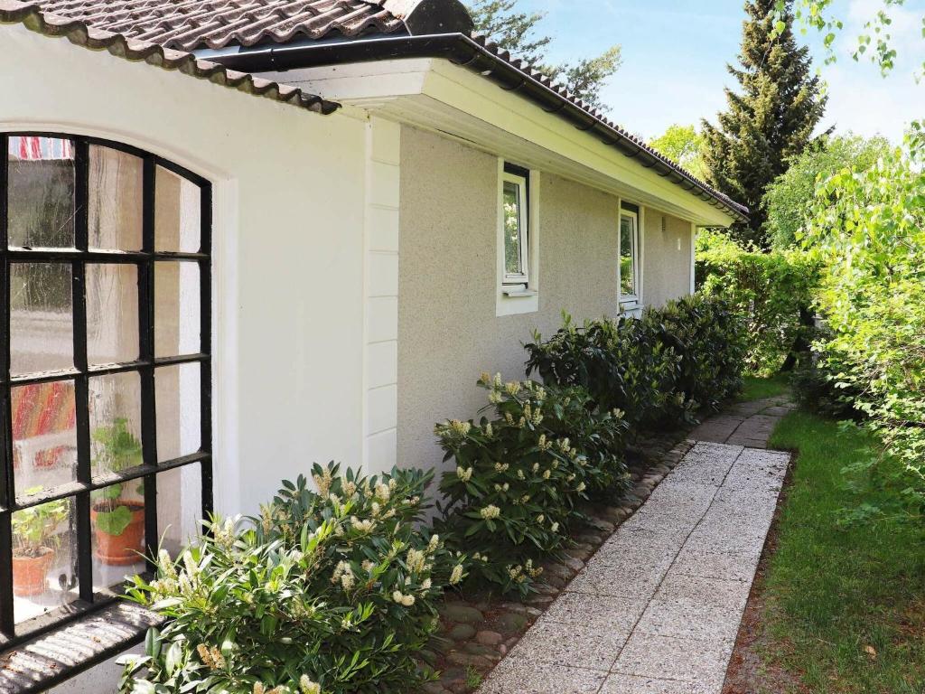 侯維肯的住宿－3 person holiday home in H LLVIKEN，一间白色的小房子,有窗户和灌木丛