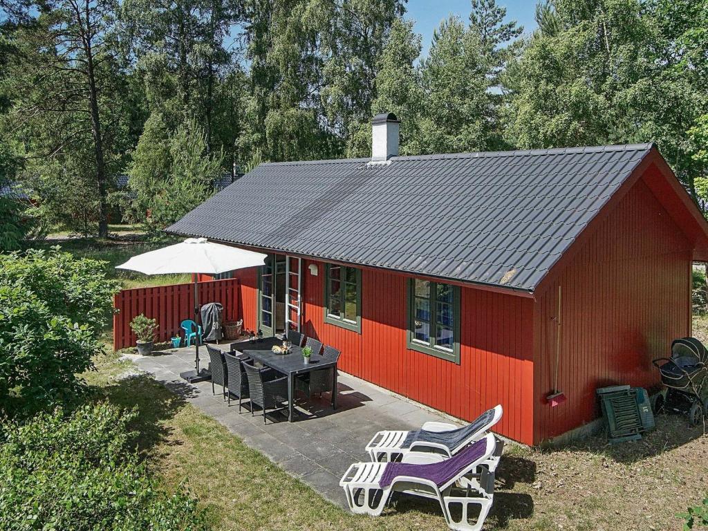 een rood huis met een tafel en stoelen ervoor bij 6 person holiday home in Nex in Snogebæk