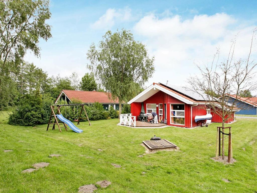 a playground in front of a red house with a slide at 6 person holiday home in Otterndorf in Otterndorf