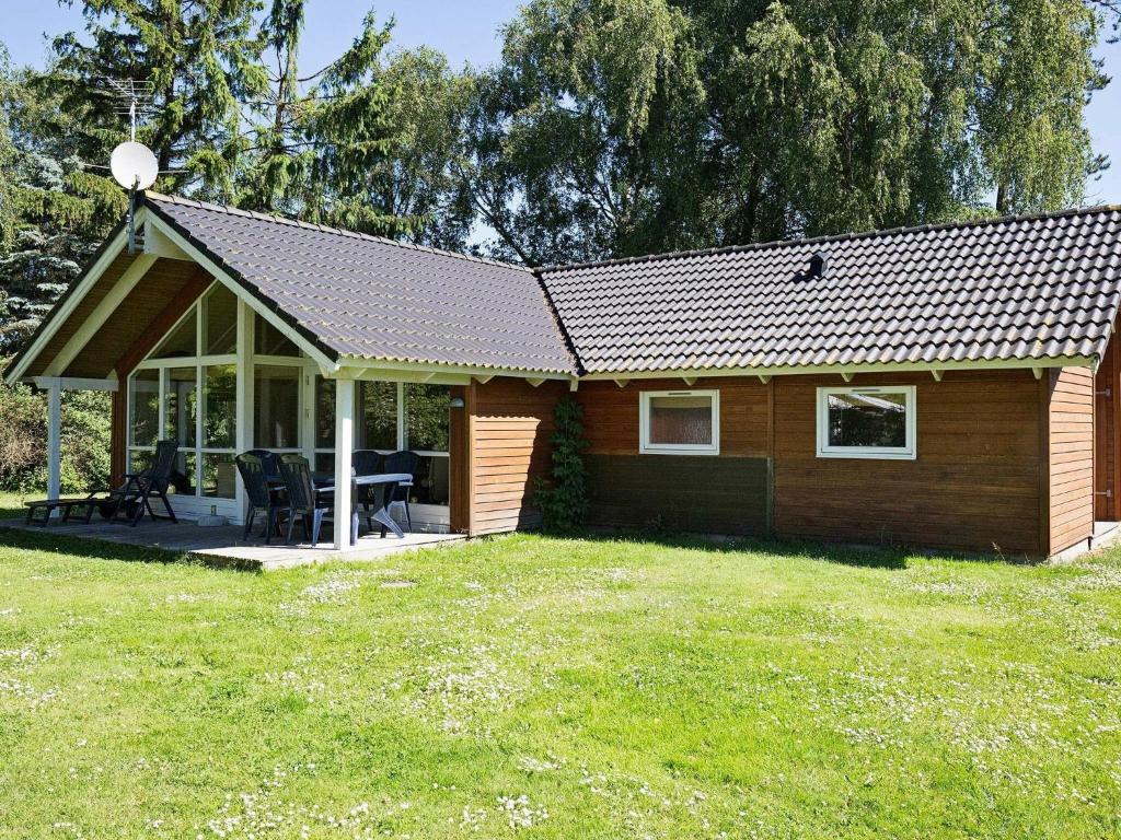 HøjbyにあるThree-Bedroom Holiday home in Højby 1の小さな木造のキャビン(ポーチ付)