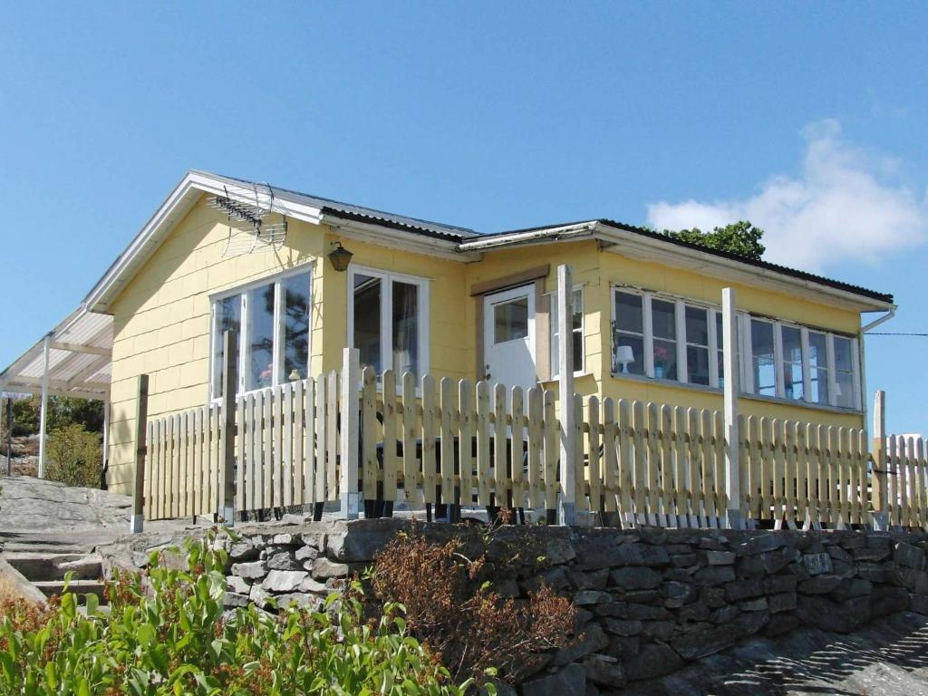 a yellow house with a fence in front of it at Two-Bedroom Holiday home in Kärna 1 in Lycke