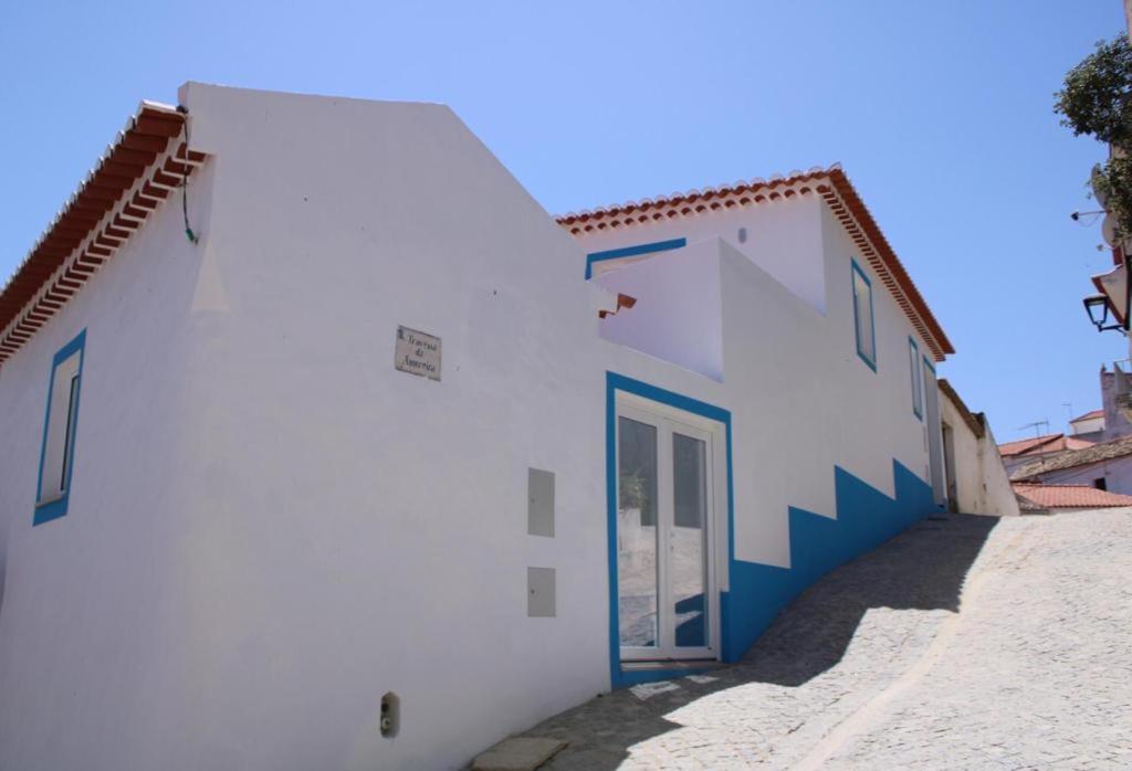 een wit gebouw met een deur aan de zijkant bij Sudoeste Guest House in Odeceixe