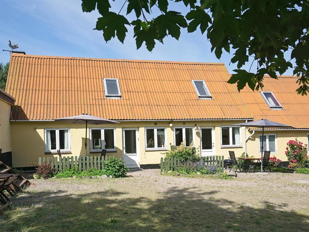 a yellow house with an orange roof and a yard at Two-Bedroom Holiday home in Svaneke 4 in Svaneke