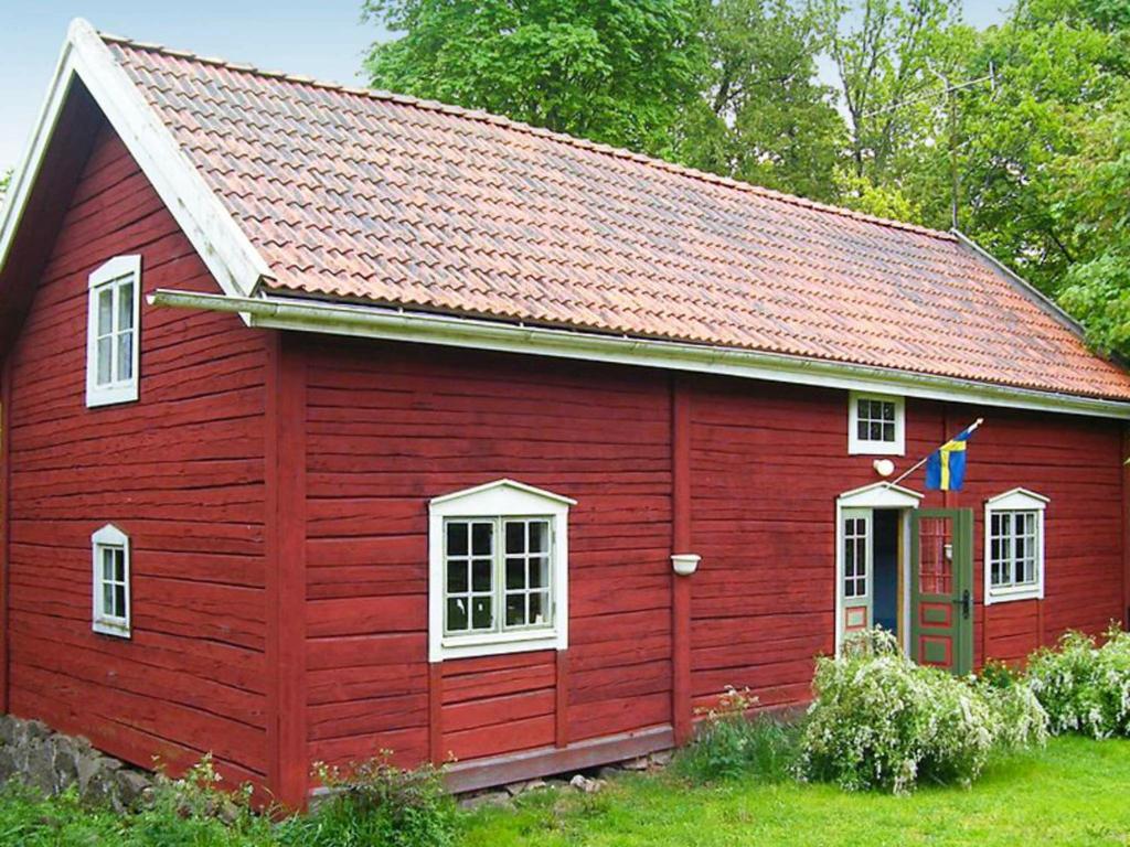 a red house with a red roof and white windows at 8 person holiday home in VIMMERBY in Rumskulla