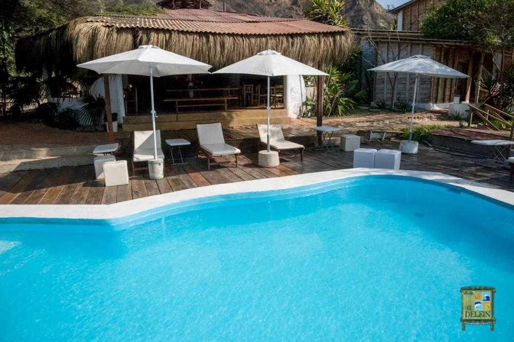 a large blue swimming pool with umbrellas and chairs at El Delfin in Zorritos