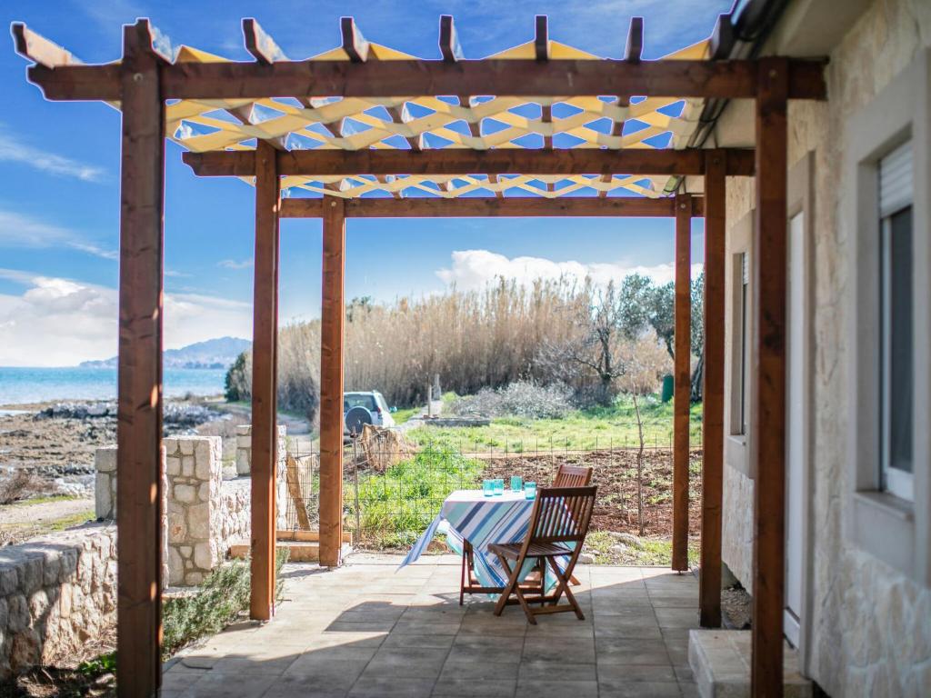 eine hölzerne Pergola mit einem Tisch und Stühlen auf einer Terrasse in der Unterkunft Secluded Holiday Home in Pa man with Sea nearby in Pašman