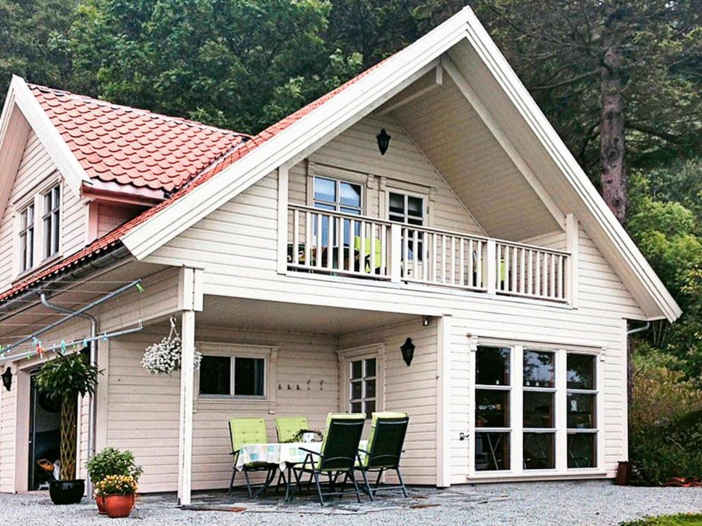 a house with a balcony and a table with chairs at 4 person holiday home in Tau in Bjørheimsbygda