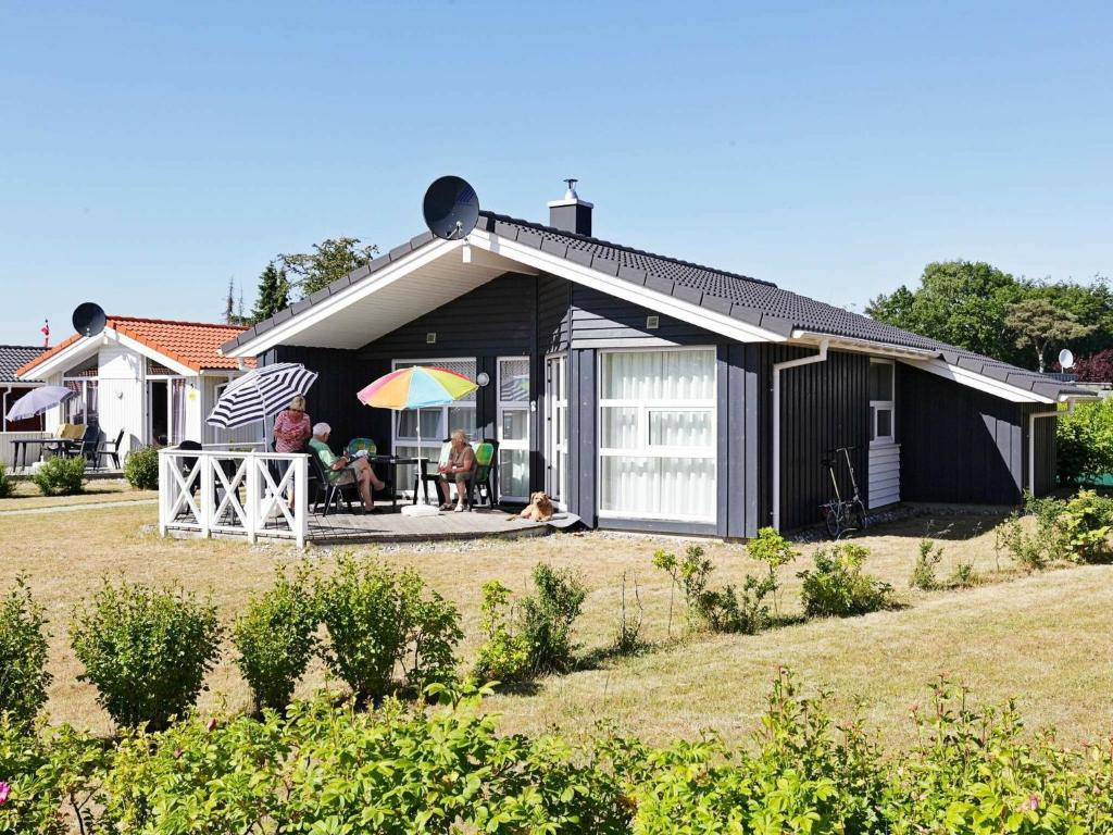una pareja sentada en el porche de una casa negra en 6 person holiday home in GROEMITZ en Grömitz