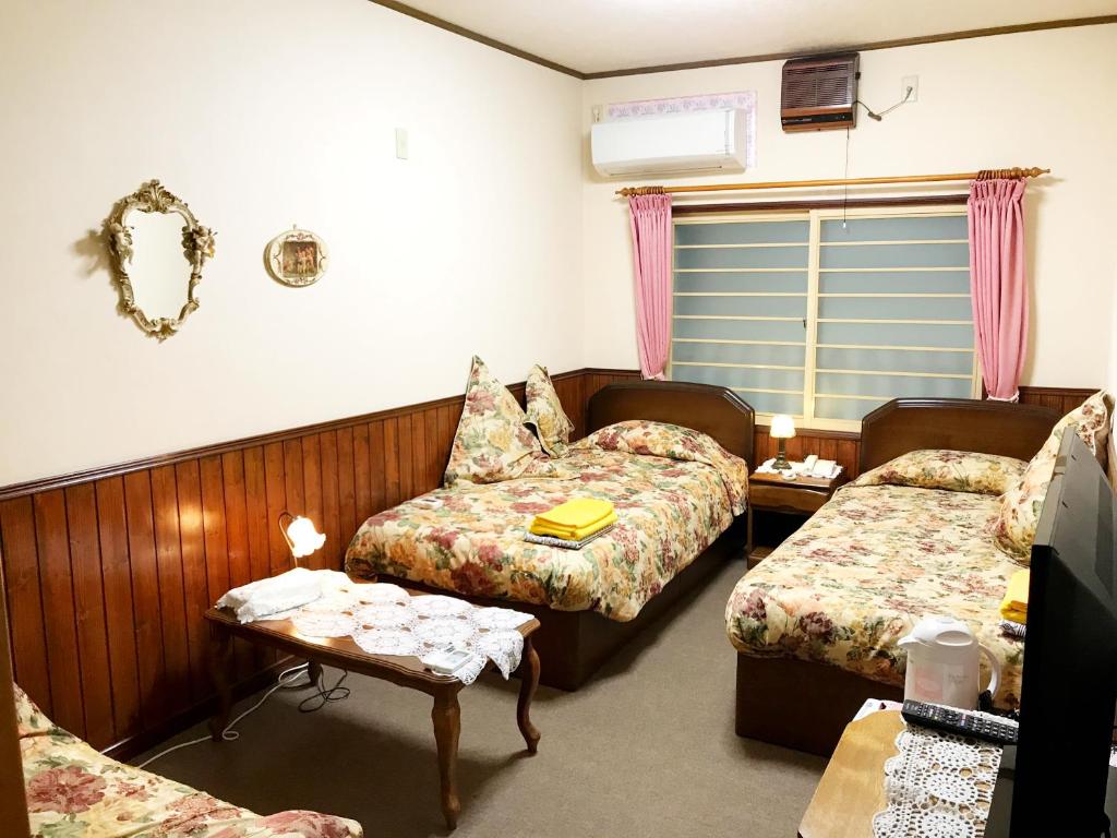Habitación con 2 camas, sofá y mesa. en Pension Puppy Tail en Hakodate