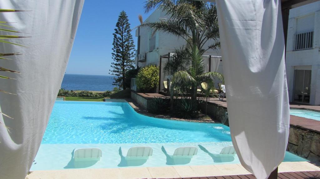 a swimming pool with chairs and the ocean at BDA Hotel & Spa in Punta del Este