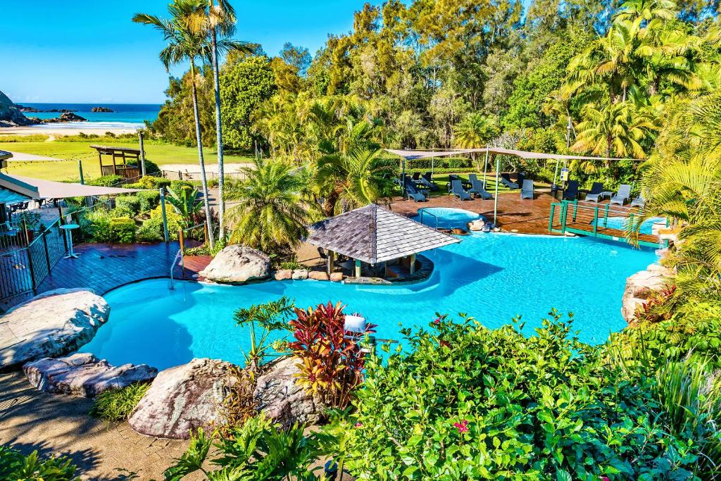 an aerial view of a resort pool with trees and the ocean at BreakFree Aanuka Beach Resort in Coffs Harbour