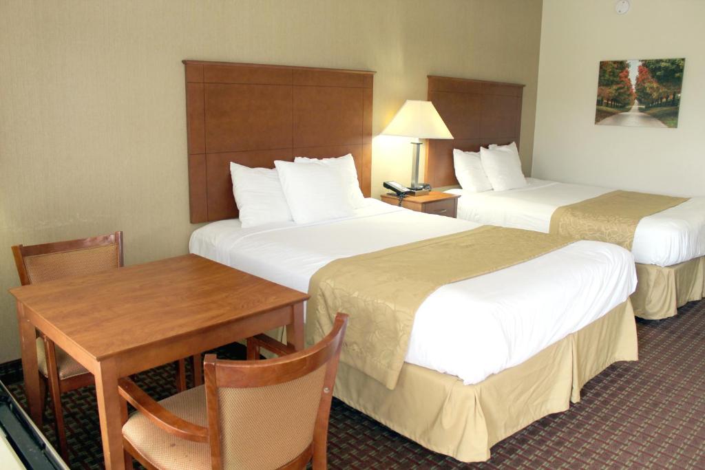 a hotel room with two beds and a table and a desk at Baymont by Wyndham Franklin in Franklin