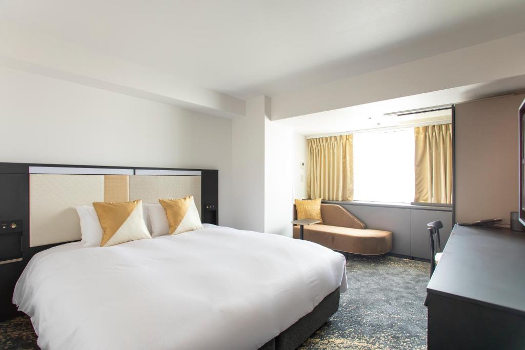 a hotel room with a large white bed and a window at Cross Hotel Osaka in Osaka
