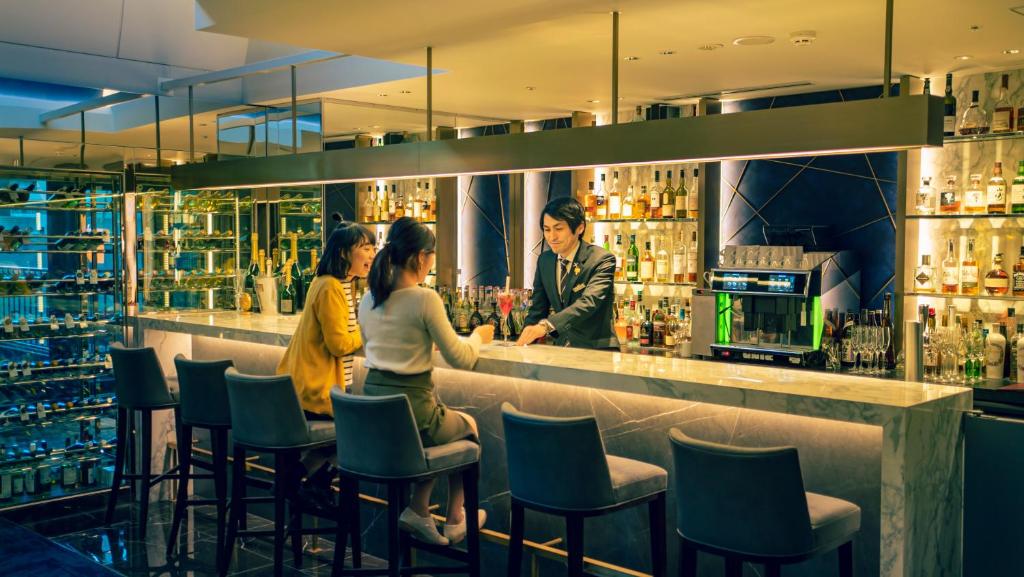 a group of people sitting at a bar at Cross Hotel Osaka in Osaka