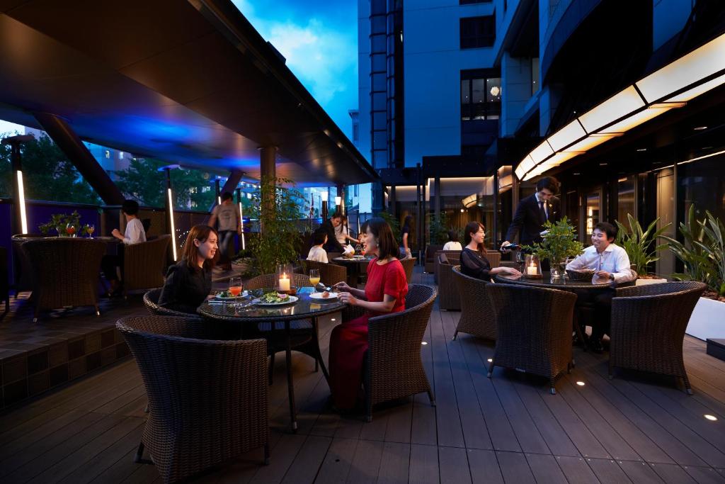 a group of people sitting at tables in a restaurant at Cross Hotel Osaka in Osaka