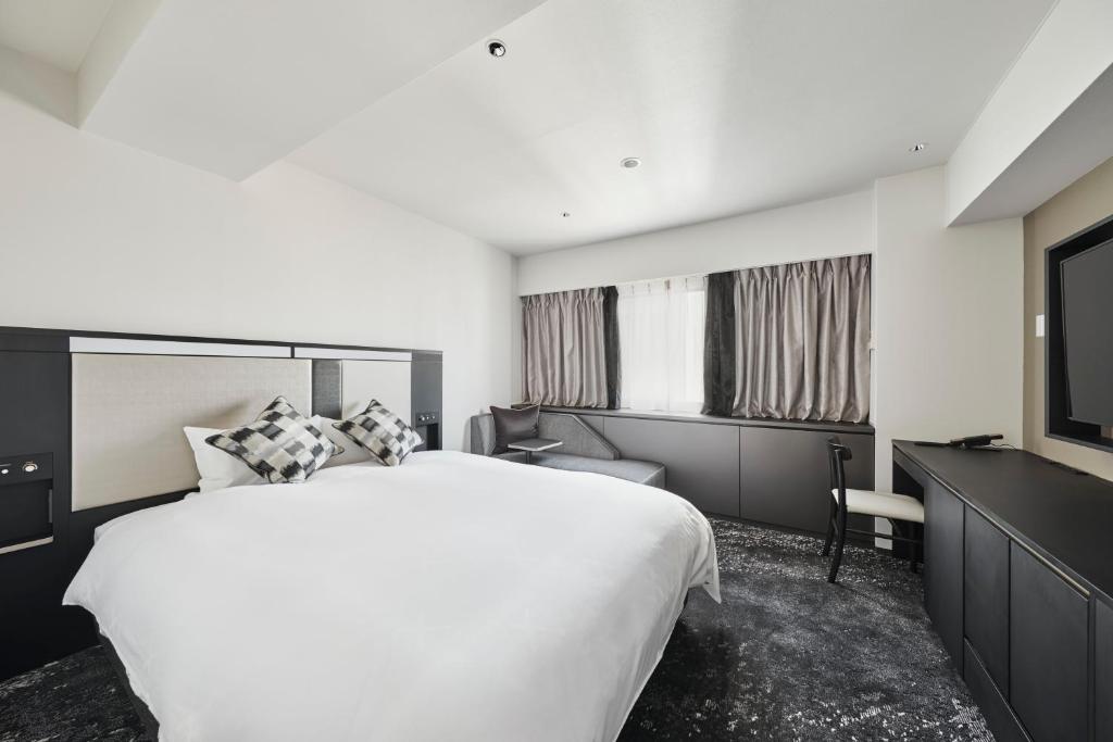 a hotel room with a large bed and a television at Cross Hotel Osaka in Osaka