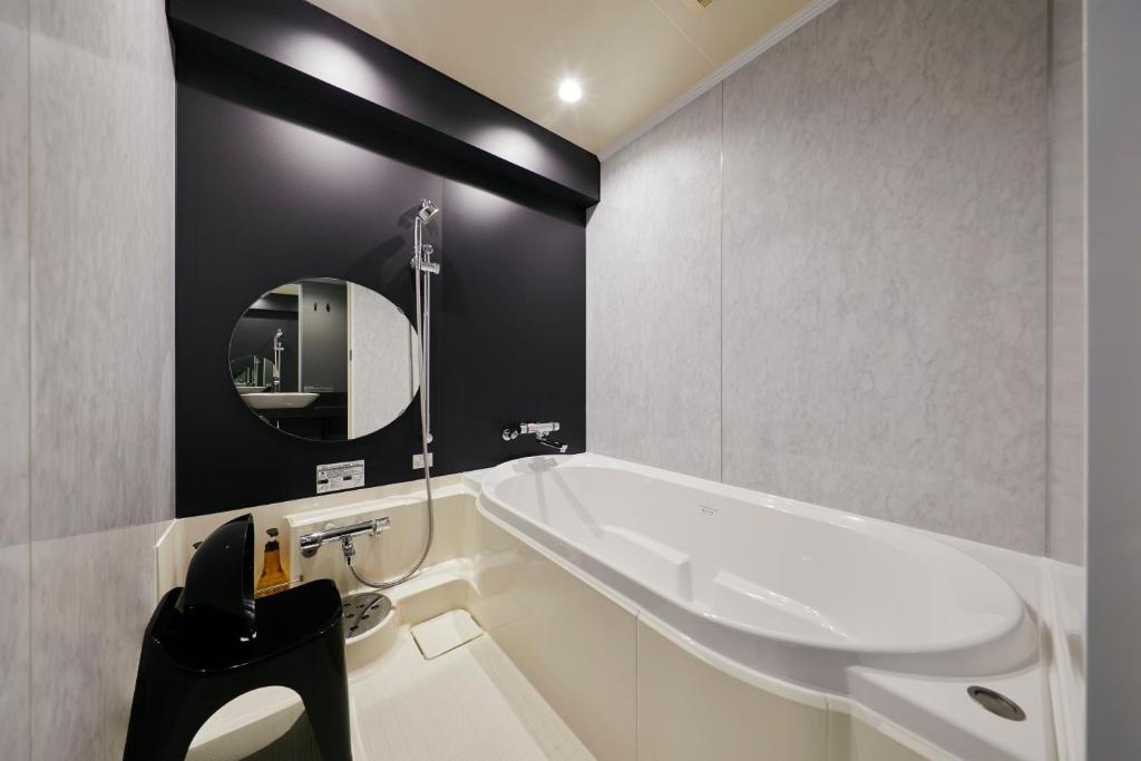 a bathroom with a tub and a sink and a mirror at Cross Hotel Osaka in Osaka