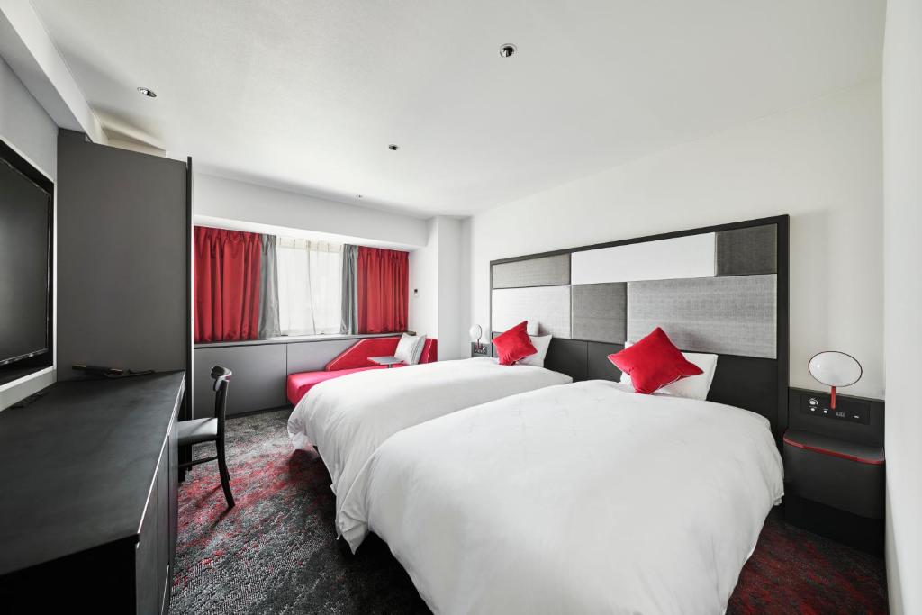 a hotel room with two beds with red pillows at Cross Hotel Osaka in Osaka