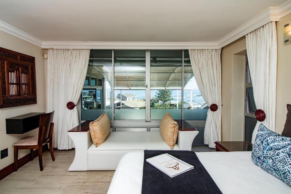 a living room with a white couch and a window at Blaauw Village Guest House in Bloubergstrand