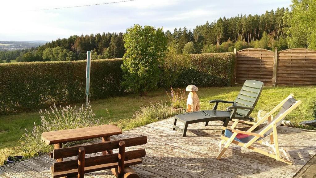 a dog standing on a patio with two lawn chairs at Ferienwohnung Steinwald Ausläufer mit Blick auf Kösseine in Waldershof