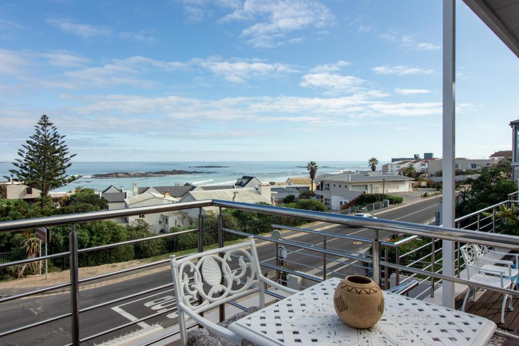 a table and chairs on a balcony with a view of the ocean at Blaauw Village Guest House in Bloubergstrand