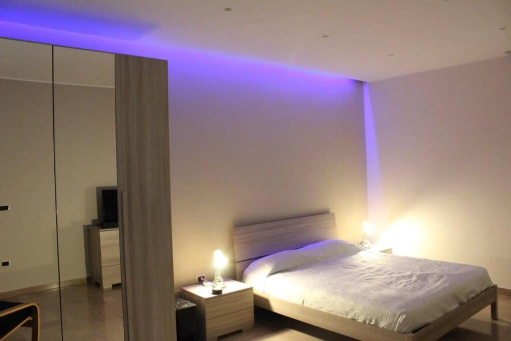 a bedroom with a bed with purple lights on it at casa vacanze COL.MAR. in Turi