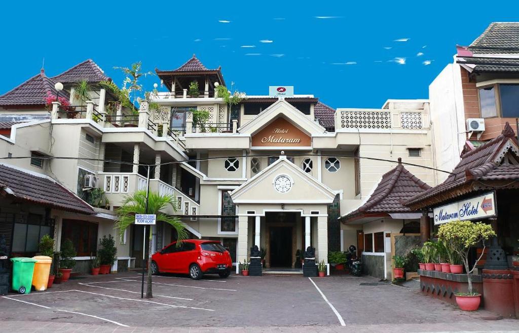 een rode auto geparkeerd voor een gebouw bij Hotel Mataram Malioboro in Yogyakarta