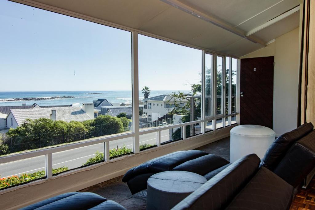 a living room with a couch and large windows at Blaauw Village Guest House in Bloubergstrand