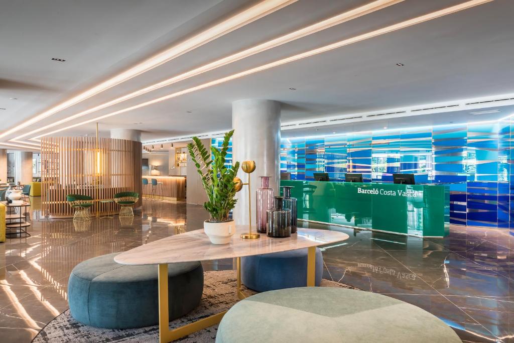 a lobby with a table and chairs in a building at Barceló Costa Vasca in San Sebastián