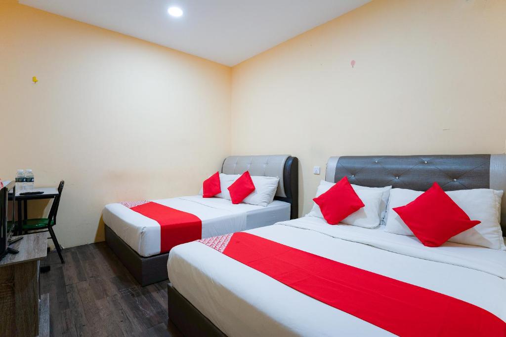 two beds in a room with red pillows at Super OYO 89807 My Budget Home in Batu Ferringhi