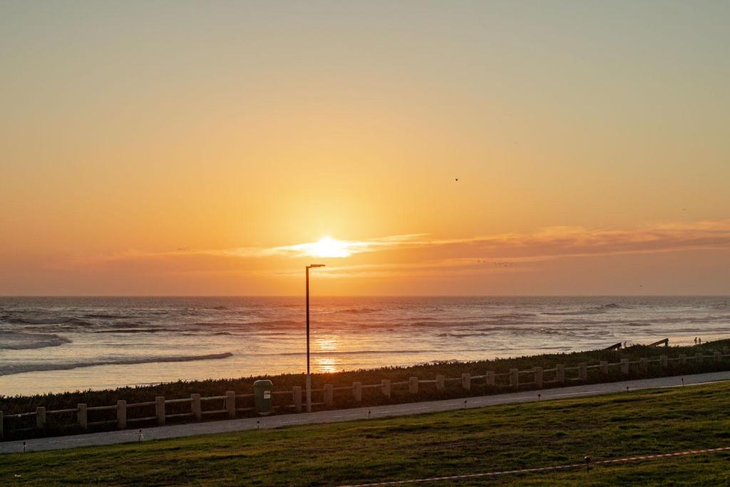 a sunset over the ocean with a street light at Blaauw Village Guest House in Bloubergstrand