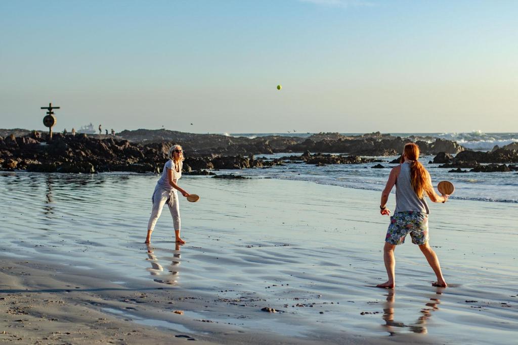 two people playing with a frisbee on the beach at Blaauw Village Guest House in Bloubergstrand