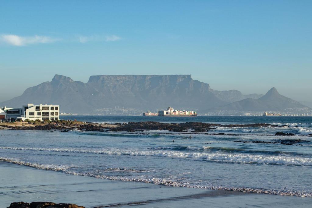 a view of the beach with mountains in the background at Blaauw Village Guest House in Bloubergstrand