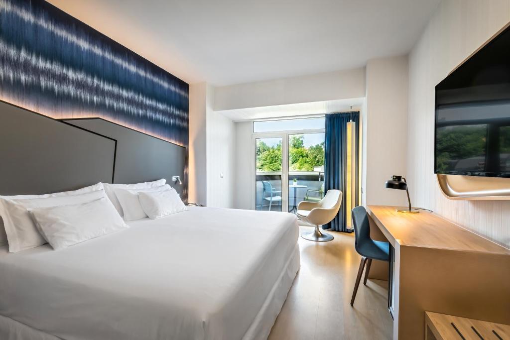 a hotel room with a large white bed and a desk at Barceló Costa Vasca in San Sebastián